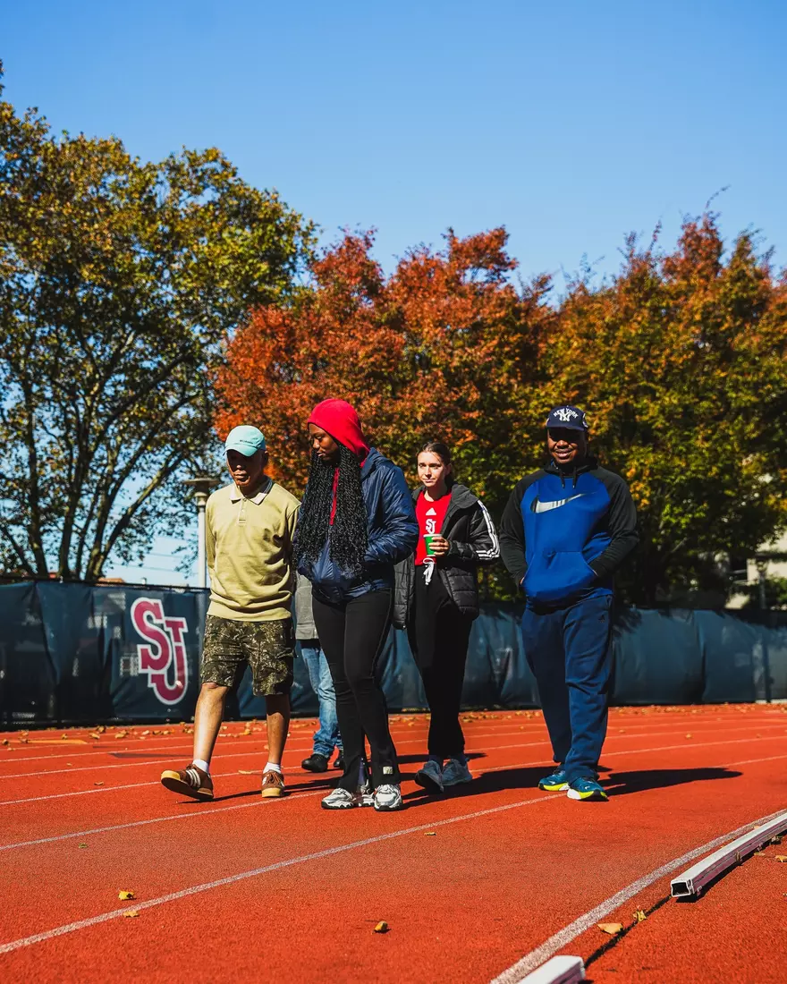 Members of QCP and SJUTF walking the track at the DaSilva Athletic Complex.
