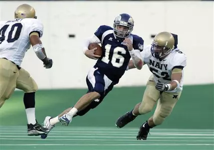 Rice quarterback Chase Clement runs the ball between Navy defenders for a 20-yard gain.