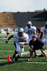 Jonathan Cary heads upfield in a drill while James Casey (40) and coach Craig Naivar look on