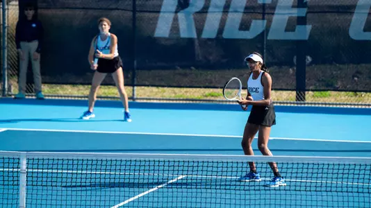 Rice women's tennis players Nithesa Selvaraj (front) and Divna Ratkovic (back) prepare to return serve in a recent doubles match.