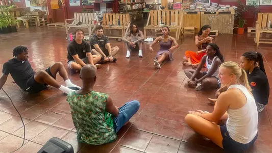 A group of Spider student-athletes sit in a circle following a lesson in Afro-Carribean dance in Costa Rica.