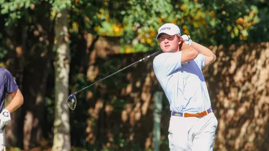 Owen Pearce holds his driver over his shoulder and stares down the flight of his tee shot.