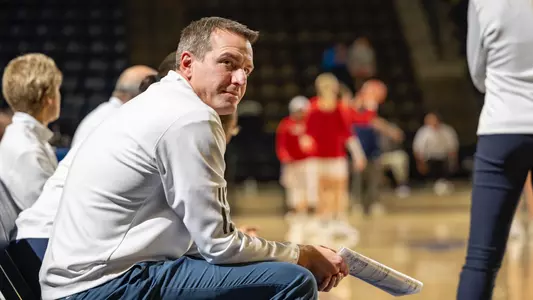 Aaron Roussell sitting on the bench pregame before a Women's Basketball game