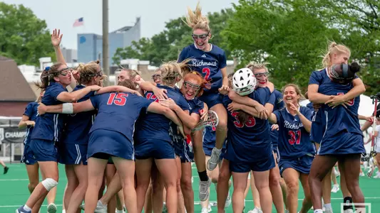Richmond women's lacrosse team jumping up in down in large group after winning the Atlantic 10 Championships in 2023