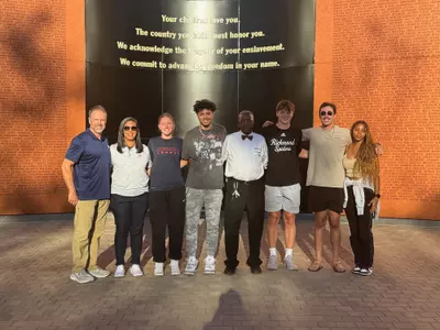 A group of student and administrators pose in front of a museum
