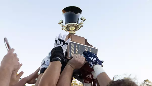 the Capital Cup being hoisted in the air by the football team after winning it in 2023