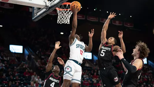 Mikkel Tyne attempts a reverse layup in the middle of three UMass players
