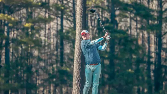 Lou Baker holds his club in the air after his drive.