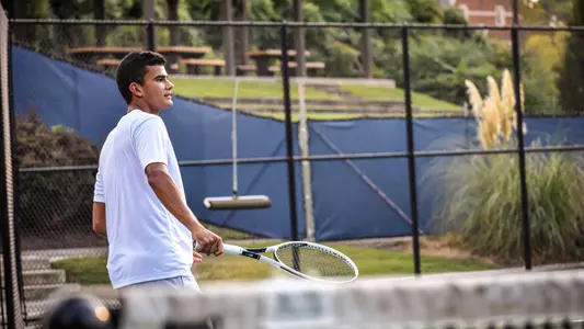 Sebastian Miano hitting the ball back over the net