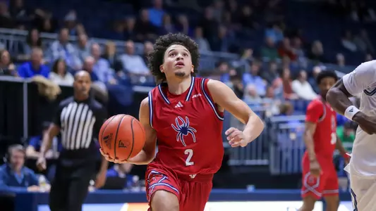 Jordan King looks up toward the rim as he drives to the basket at Rhode Island