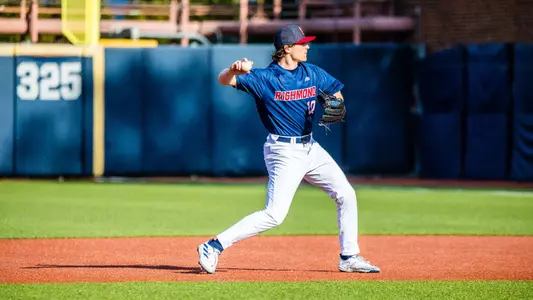 Jake Topolski, wearing a blue jersey and white pants, is mid action to throw the ball to first base.