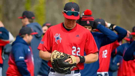 Joey Wilga, wearing a red number 22 jersey, inspects his first base mitt