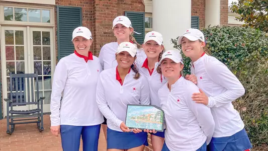 Women's golf team poses with its trophy after winning the RiverTowne Invitational