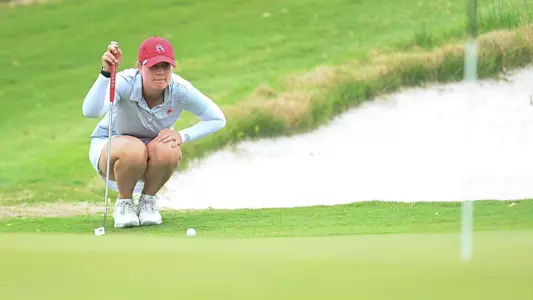 Rory Weinfurther squats on the green to line up her putt