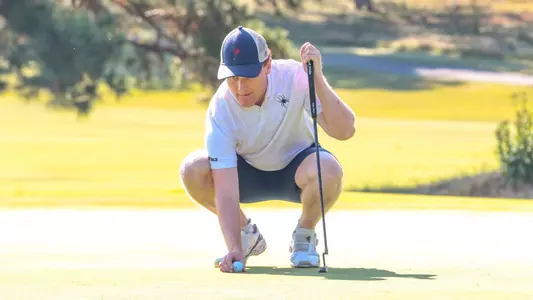 Cole Ekert squats to line up a putt on the green
