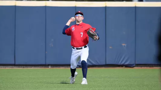 Jackson Kraemer in a red Richmond jersey top and white pants throws the ball in from the outfield