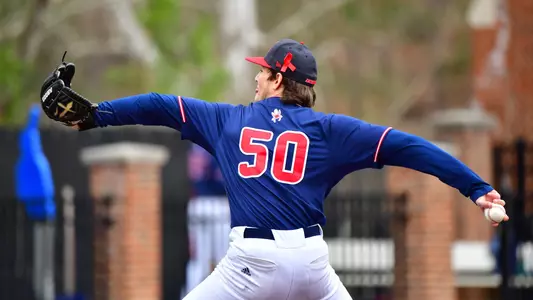 Dane Armson, number 50 in red lettering on blue jersey, is fully extended pitching the ball