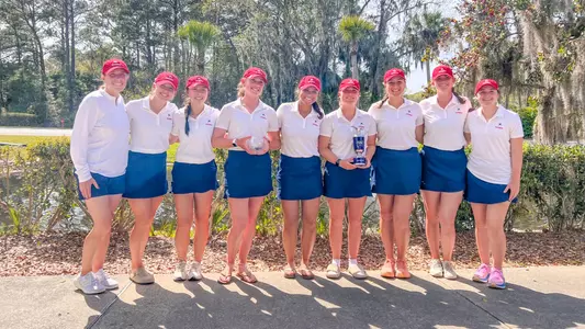 Spider women's golfers line up side-by-side with trophies the team won at the Low Country Intercollegiate