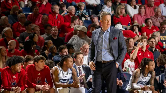 Chris Mooney stands in front of the Spiders bench at Robins Center