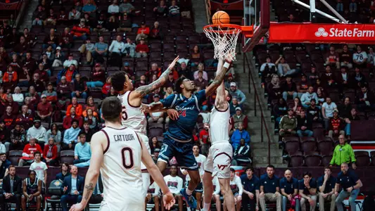 Isaiah Bigelow makes a contested layup in between two Hokies at Cassell Coliseum