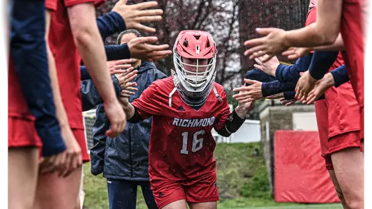 Nicole Burney running through the high-five tunnel during starting lineups with her arms out and her helmet on