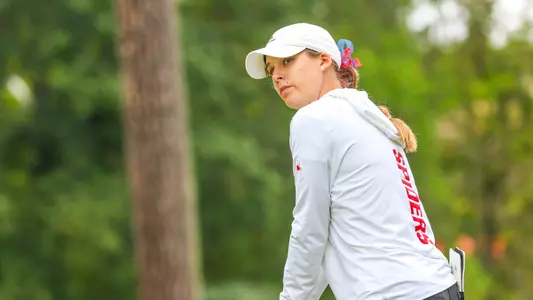 Olivia Wilkie stares down the fairway while standing over her ball on the tee box.