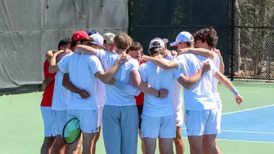 Photo of the Men's Tennis Team huddled during pregame