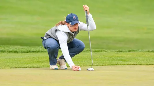 Olivia Wilkie squats to line up a putt on the green