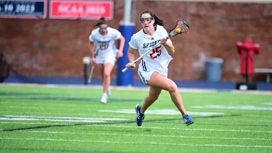 Maggie Jordan running the ball up the field through a clear, a defender is behind her
