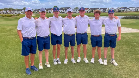 Richmond men's golf team puts their arms around each other and poses for a picture next to the 18th green