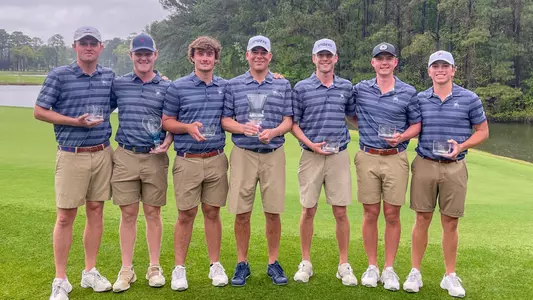 The members of the Spiders men's golf team posed with trophies on a green following their win at the AGT Collegiate