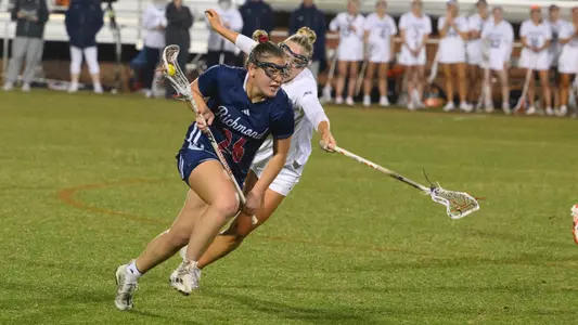 Mia Valerio running the ball up the field after scooping a ground ball, an opponent is trying to steal the ball from her