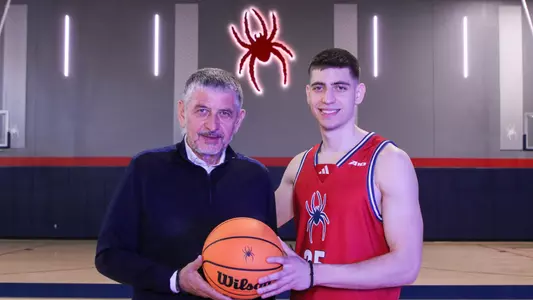 Dusan Neskovic and his father hold a basketball in the Queally Athletics Center