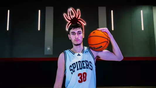 Apostolos Roumoglou holds a ball and poses in the Queally Athletics Center