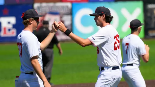 Matthew Anderson high-fives fellow pitcher Kyle Roche on his way to the dugout between innings