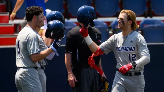 Jack Arcamone daps helmets with DJ Pacheco after hitting a home run.