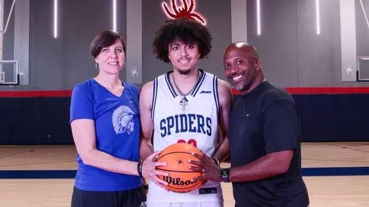 George Washington III and his parents pose in the Queally Athletics Center at midcourt