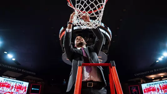 Darian Dollar cuts down a piece of the net after the Spiders won the 2024 regular season A-10 title in the Robins Center