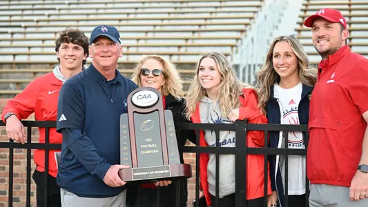 Russ Huesman and his family pose with the CAA championship trophy at William & Mary's Zable Stadium