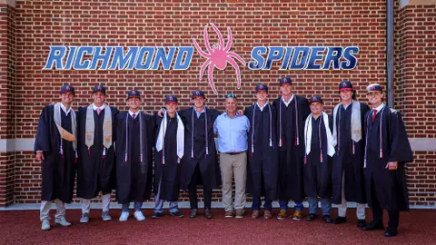 Members of Spider baseball graduating in 2024 pose in their caps and gowns with coach Mik Aoki