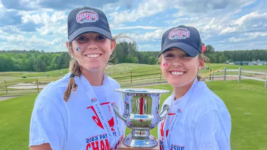 Lauren Jones and Olivia Wilkie smile while holding up the 2023 Patriot League women's golf trophy