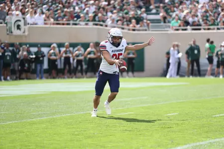 Aaron Trusler punts the ball during warmups at Michigan State