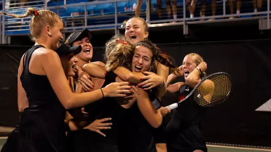 Photo of women's tennis celebrating a win in the A-10 Championship
