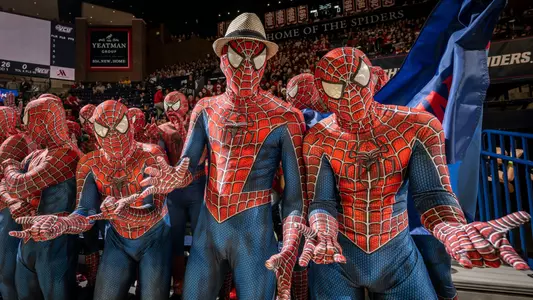 Costumed fans cheer on Spider men's basketball at a home game