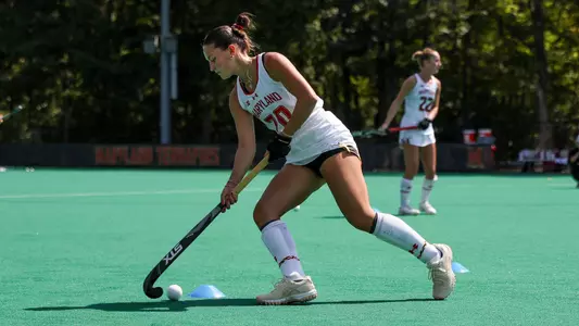 Lillian Buckwalter action shot in white University of Maryland uniform