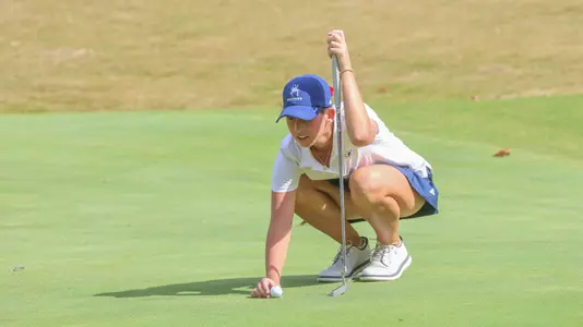 Katie Magners squats to line up a putt