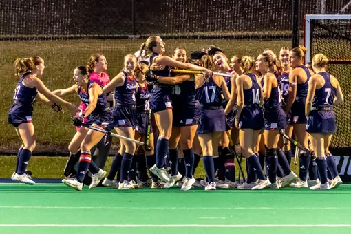 Spider field hockey wearing their blue uniforms celebrate a victory at Crenshaw Field