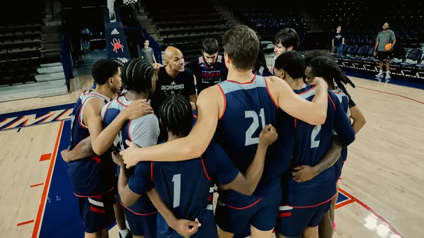 Coach David Boyden in the middle of a huddle at practice