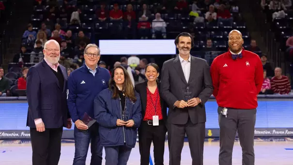 Recipients of the 2025 alumni awards pose at a men's basketball game