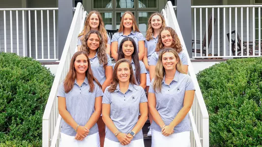 The women's golf team poses on the steps of a cabin at Independence Golf Course